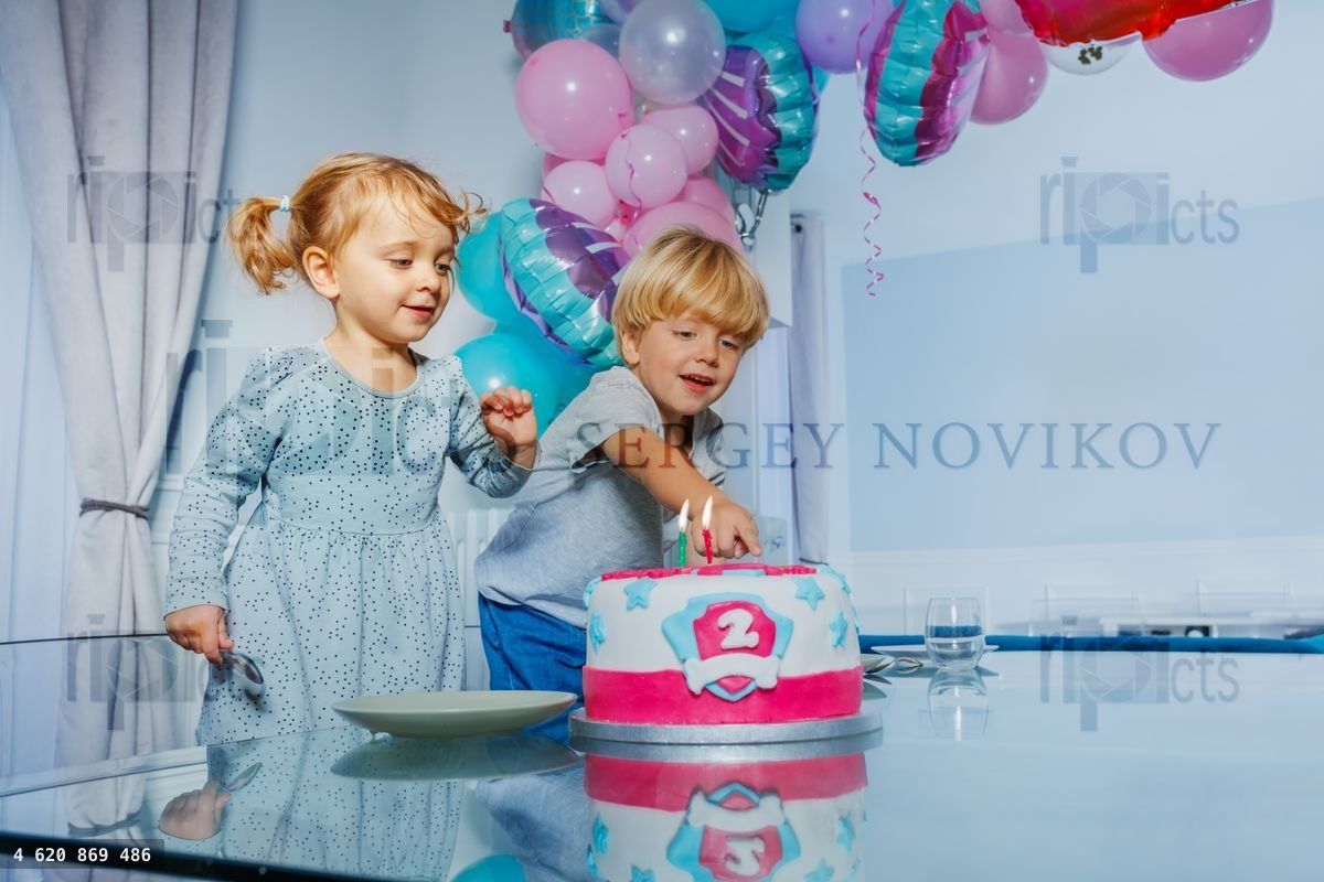 Girl and a boy sit at birthday party pointing to cake