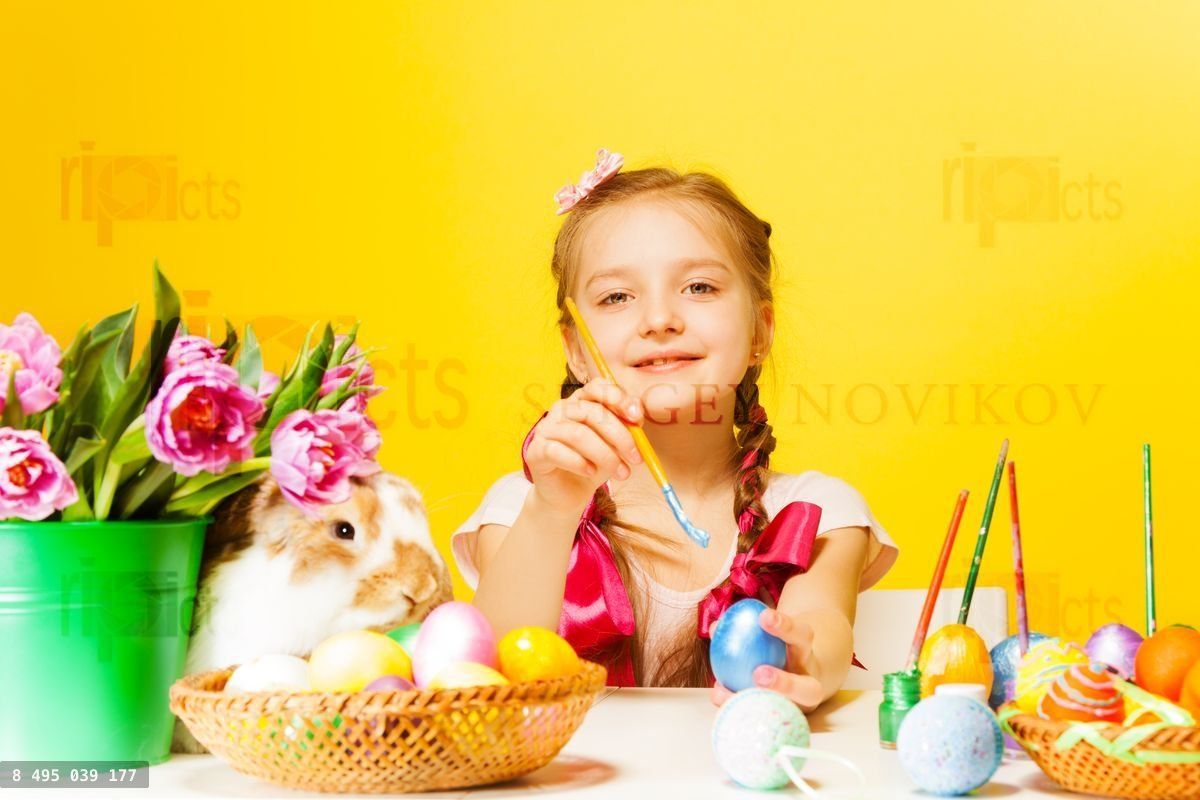 Girl colouring Eastern eggs and cute rabbit near