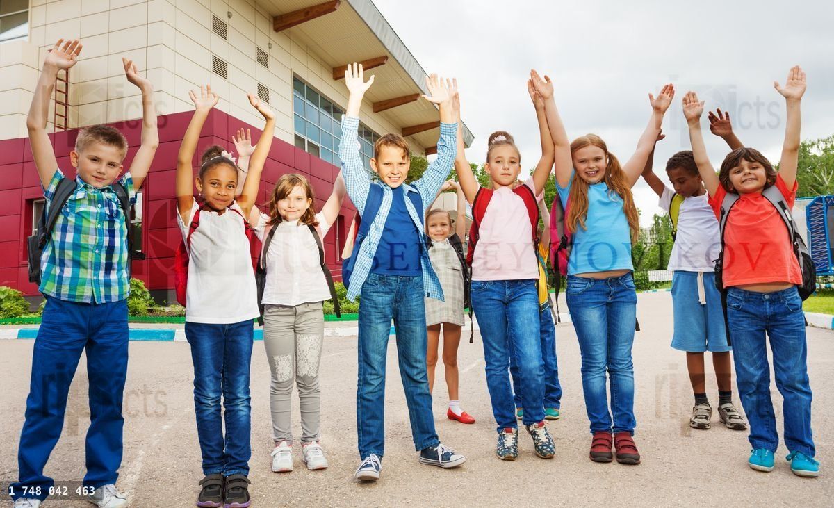 Enfants heureux avec les bras levés près de l'école