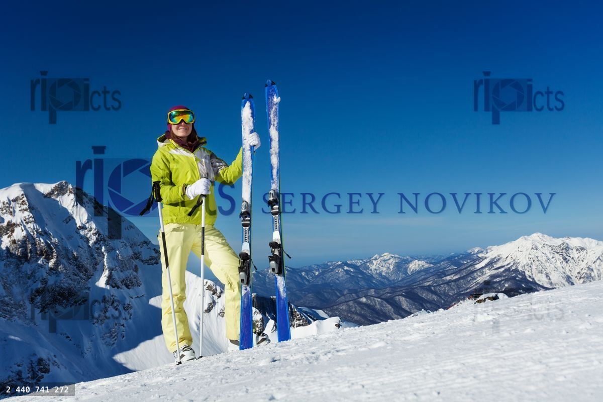 Young woman in mask stands and holds ski, poles