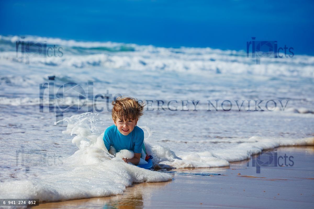 Young child playing in ocean waves at a sunny beach on vacation