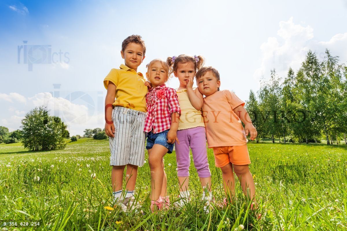 Four kids standing close to each other in meadow