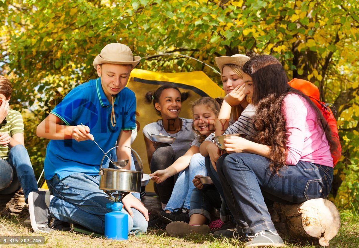 Boy cooking soup in pot for friends at campsite