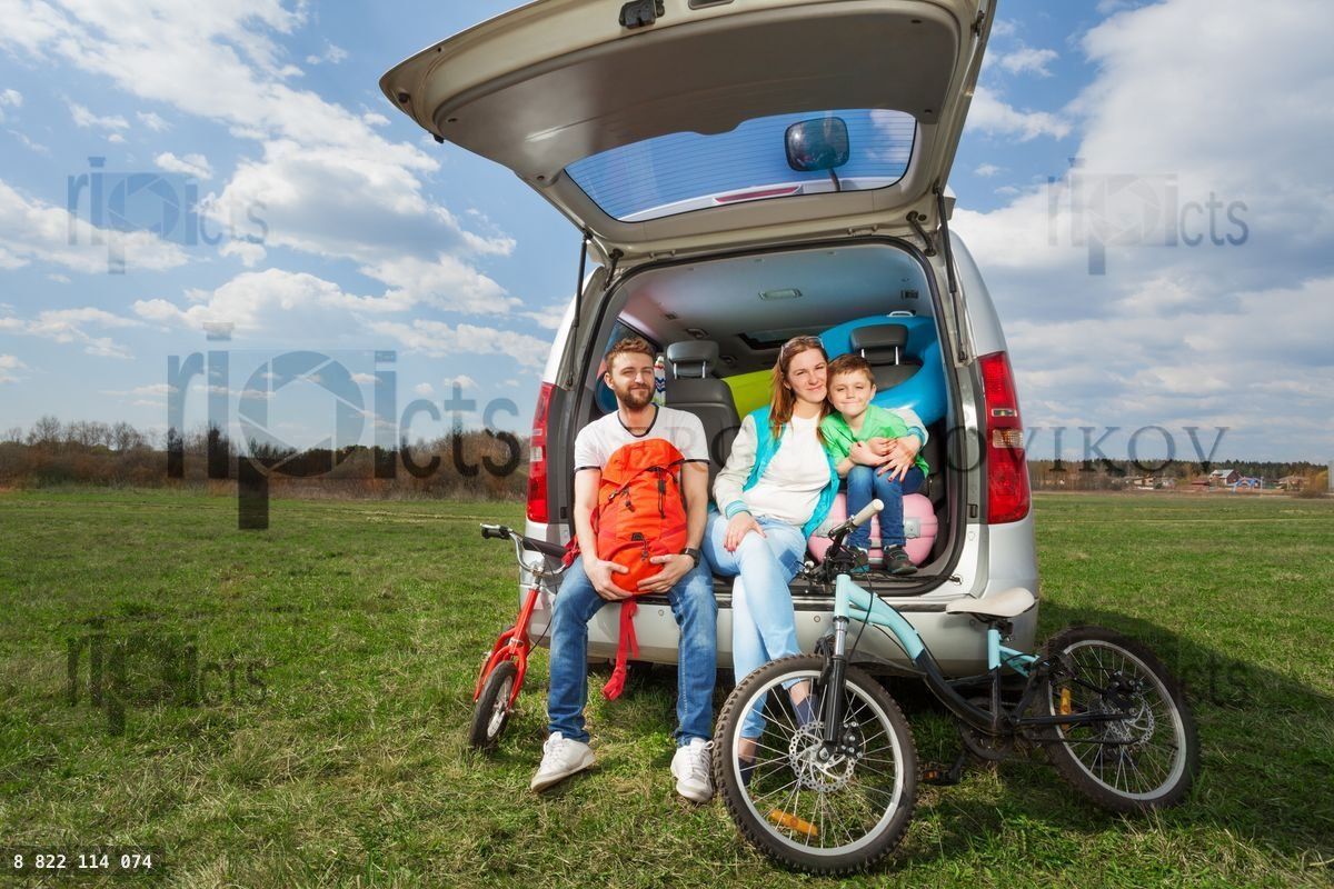 Happy family sitting in open luggage boot outside