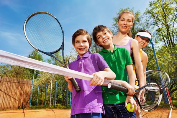 Family of tennis players standing next to the net