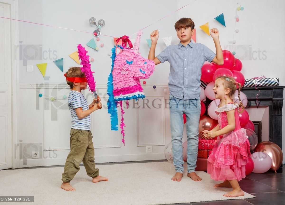 Young boy with blindfold prepare to hit colorful pinata unicorn