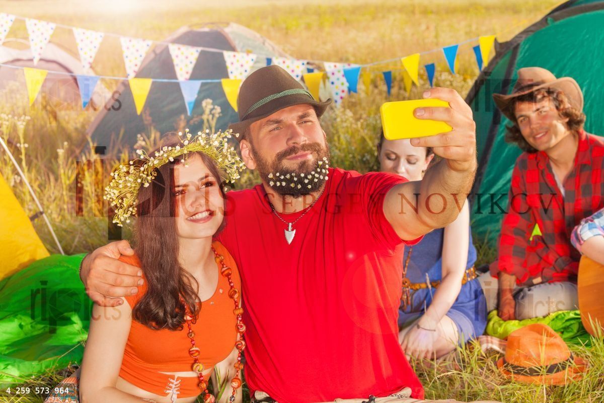 Beautiful young couple taking selfie against tents