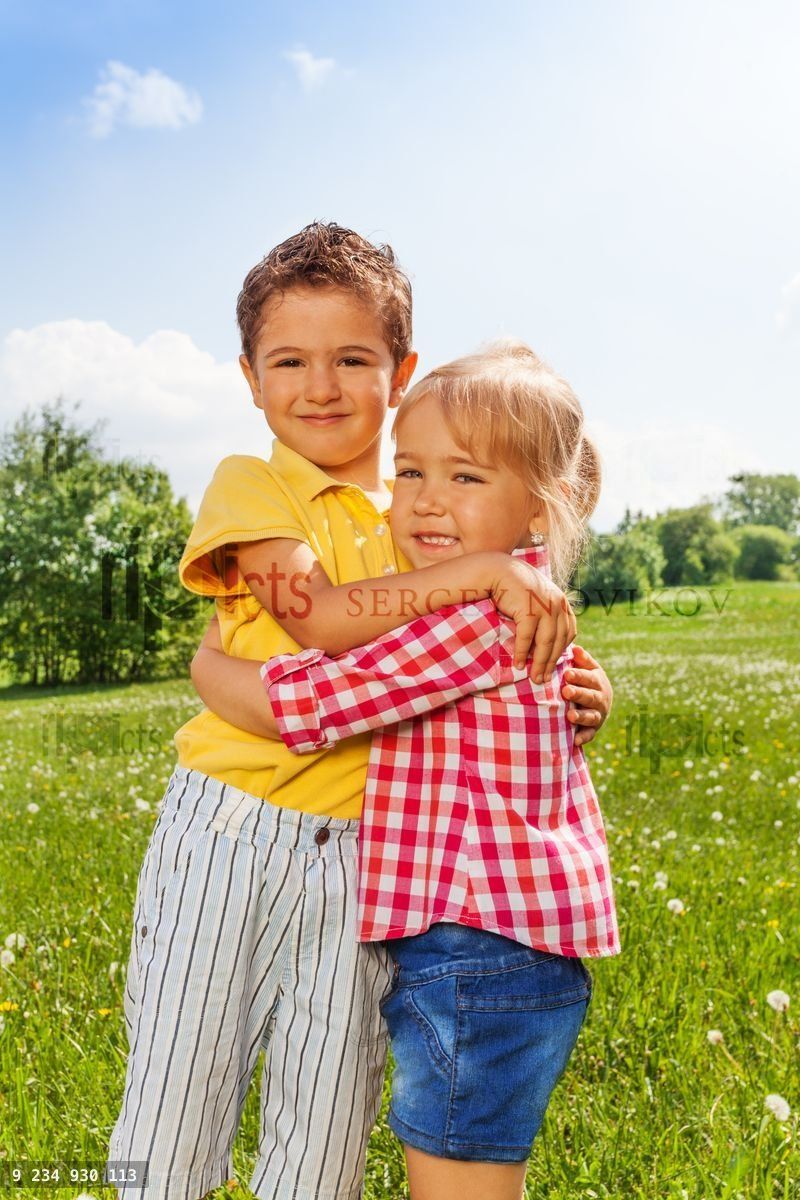 Boy and girl hugging in green field