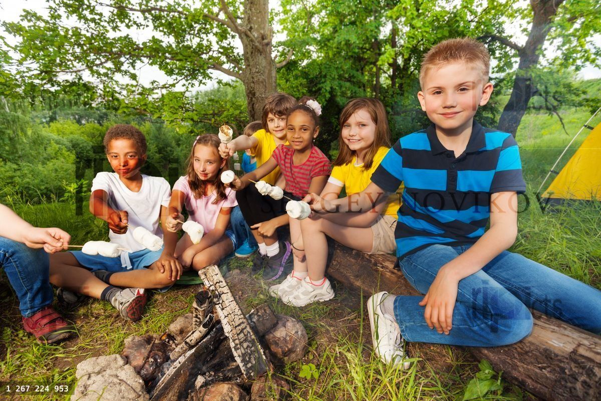Group of kids sit near bonfire with marshmallow