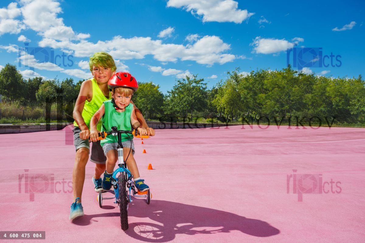 Two kids in the park boy teach brother to ride bicycle