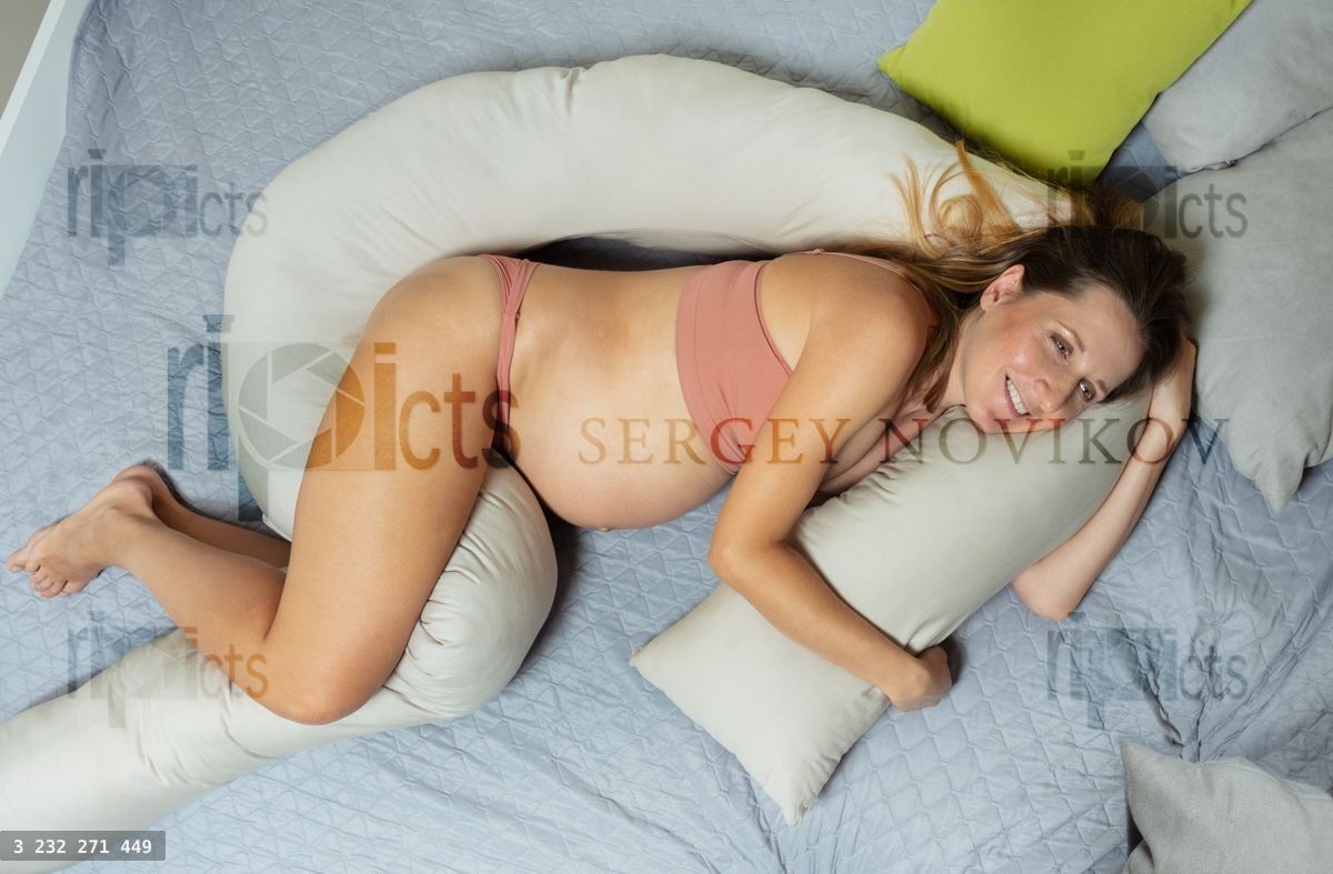 Woman lay on the bed hugging pillow for expecting