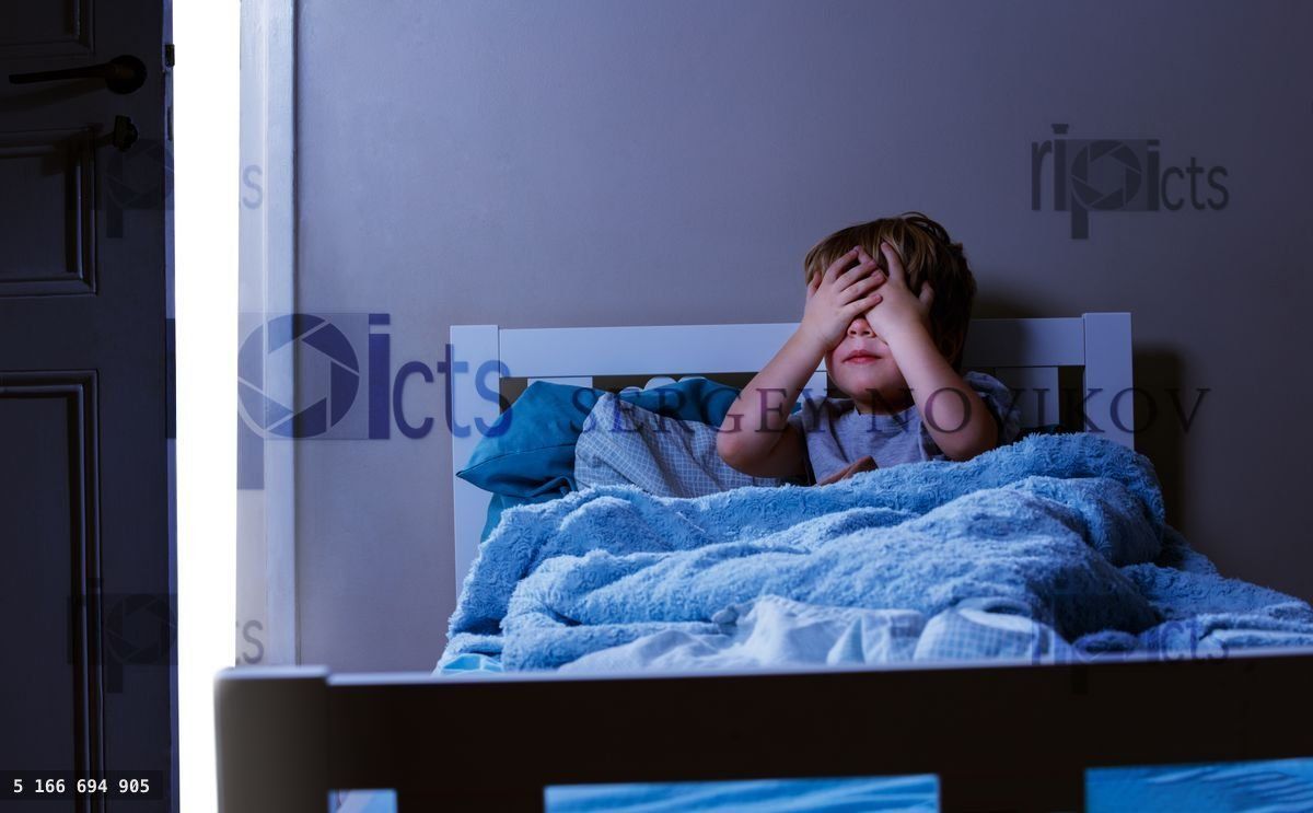 Boy in bed closing eyes - concept of children fears at bedroom