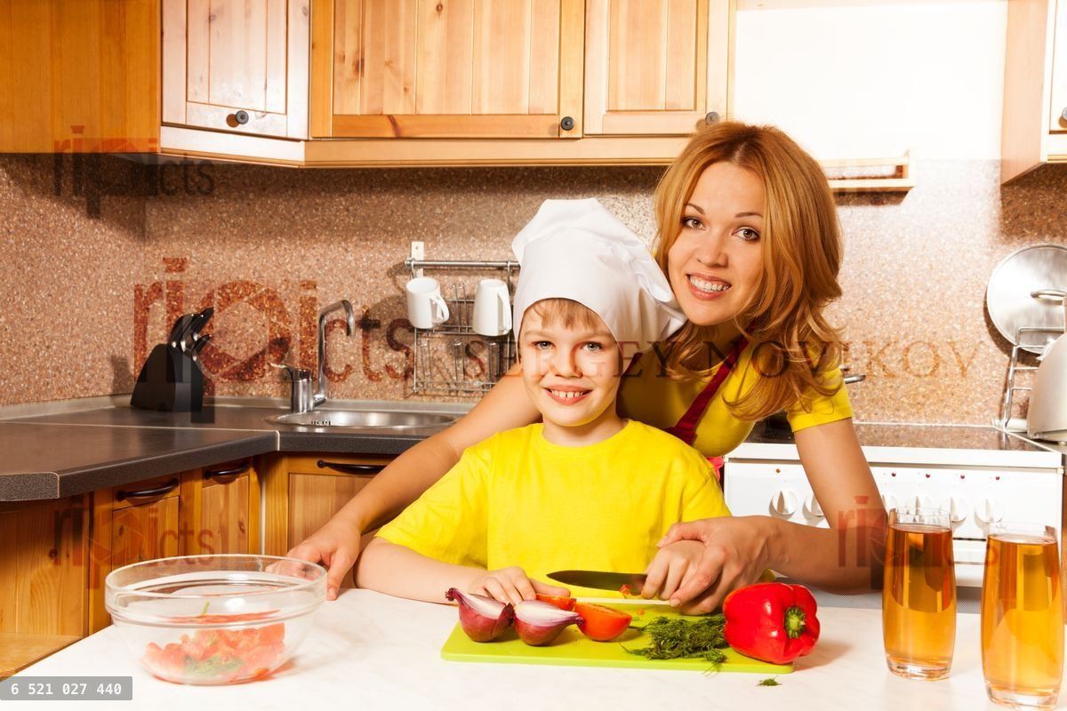 Happy boy using toque cuts vegetables with mother