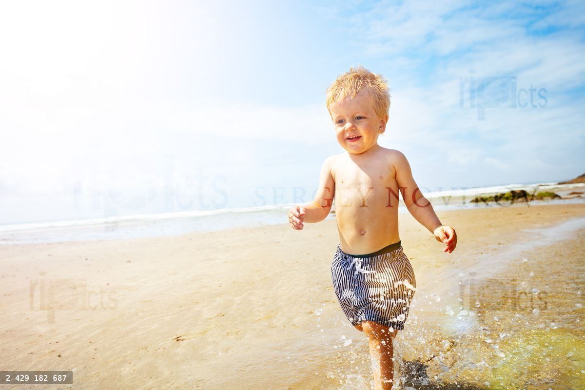 Child boy run fast and splash on a sand sea beach