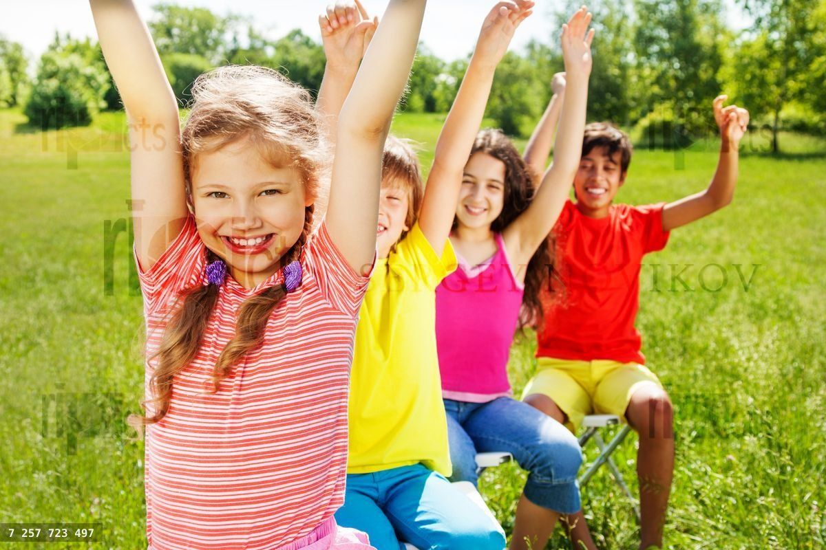 Four kids sitting in row with hands up