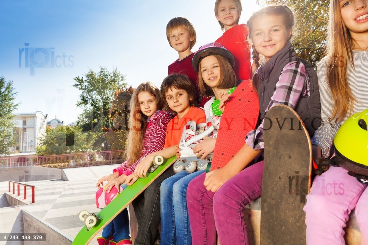 Smiling children with skateboards sit together