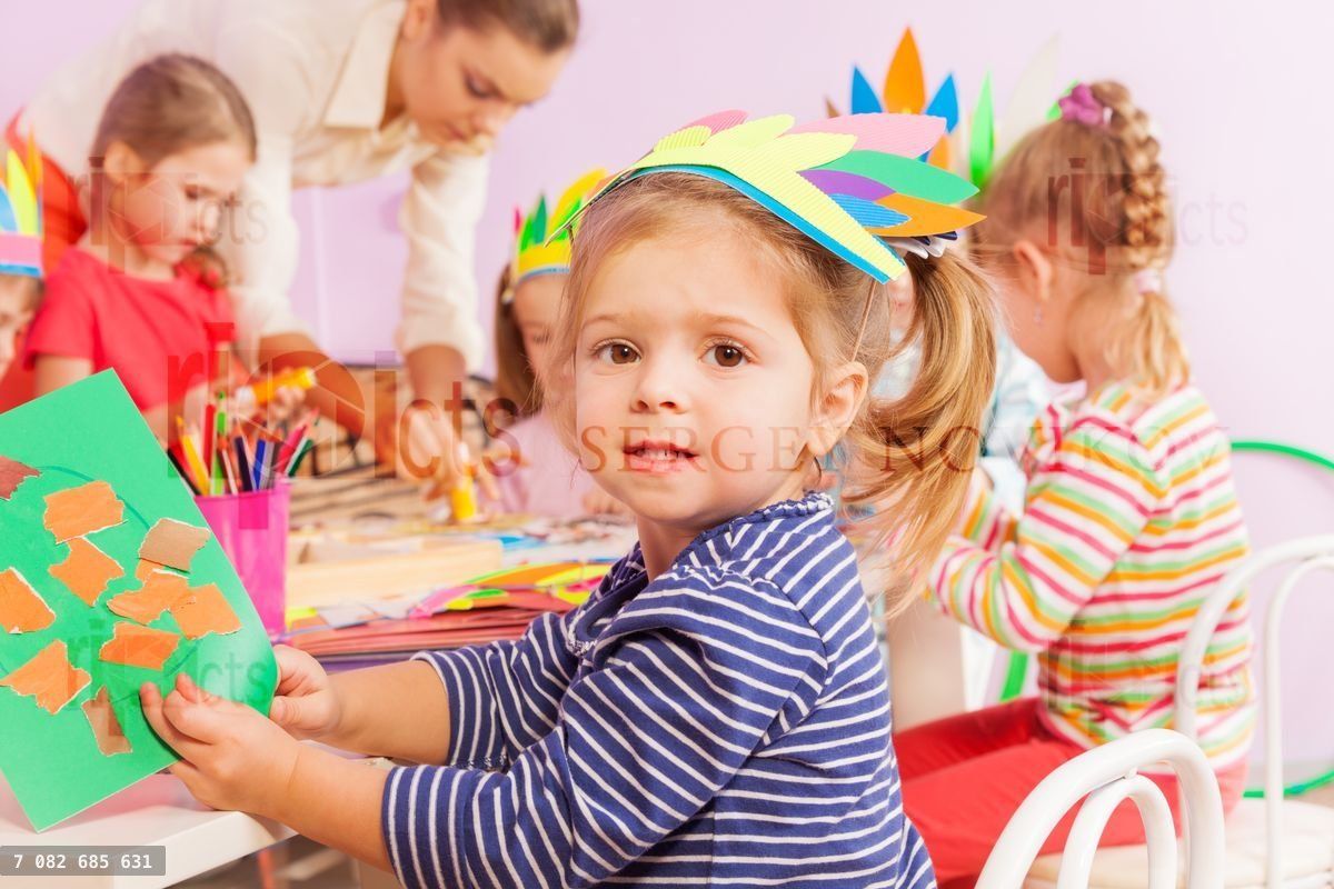 Girl glue paper in crafting kindergarten