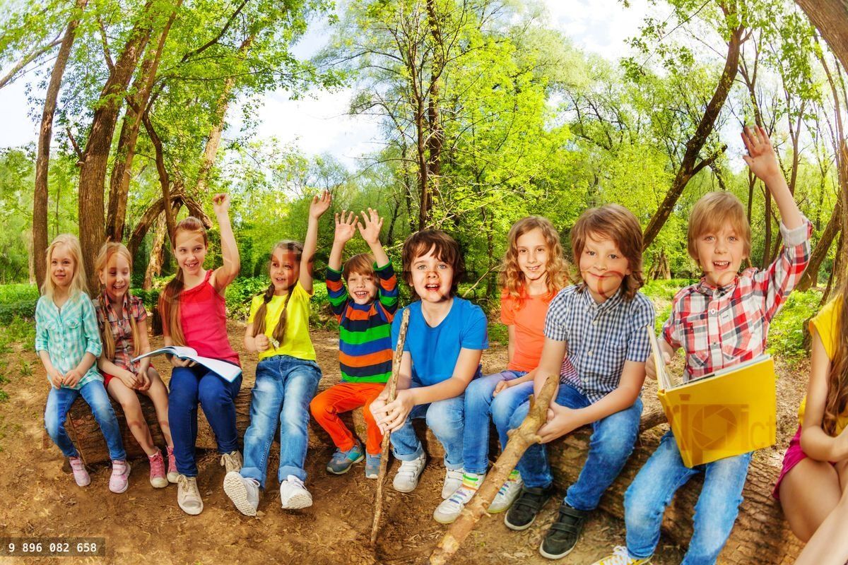 Funny kids sitting on log outdoor and reading book