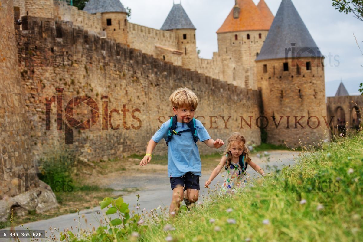 Young explorers climb hill in Carcassonne, France at summer day