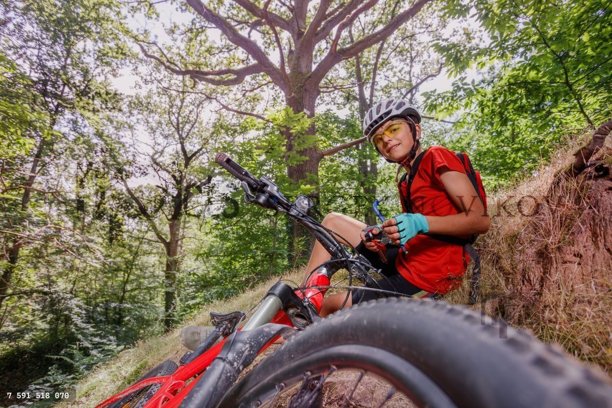Radfahrer-Kind macht eine Pause, um das Fahrrad zu reparieren, und hält ein Werkzeug in den Händen