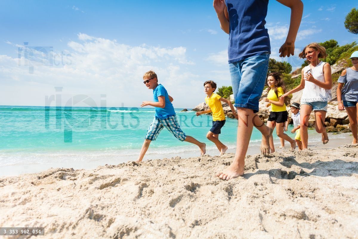 Group of happy kids running on white sand beach