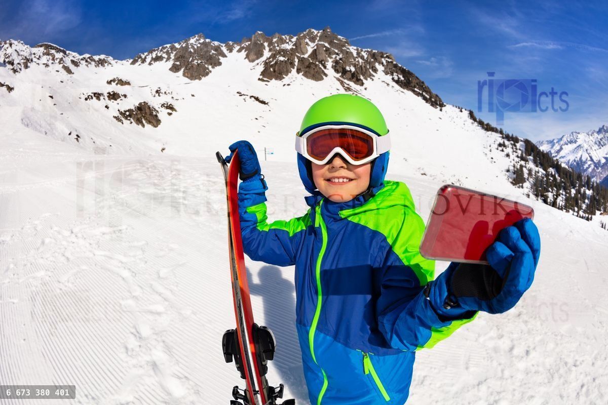Happy boy hold ski taking picture with cell phone