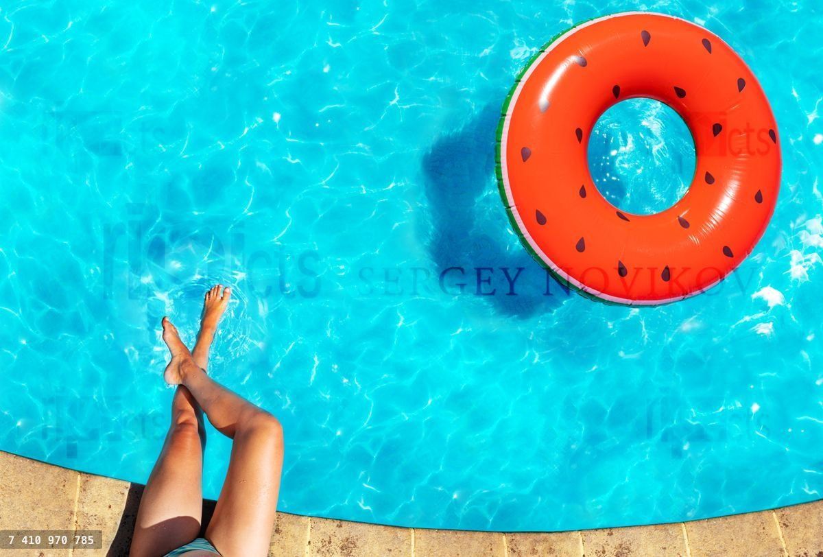 Woman's legs, inflatable watermelon swim in pool