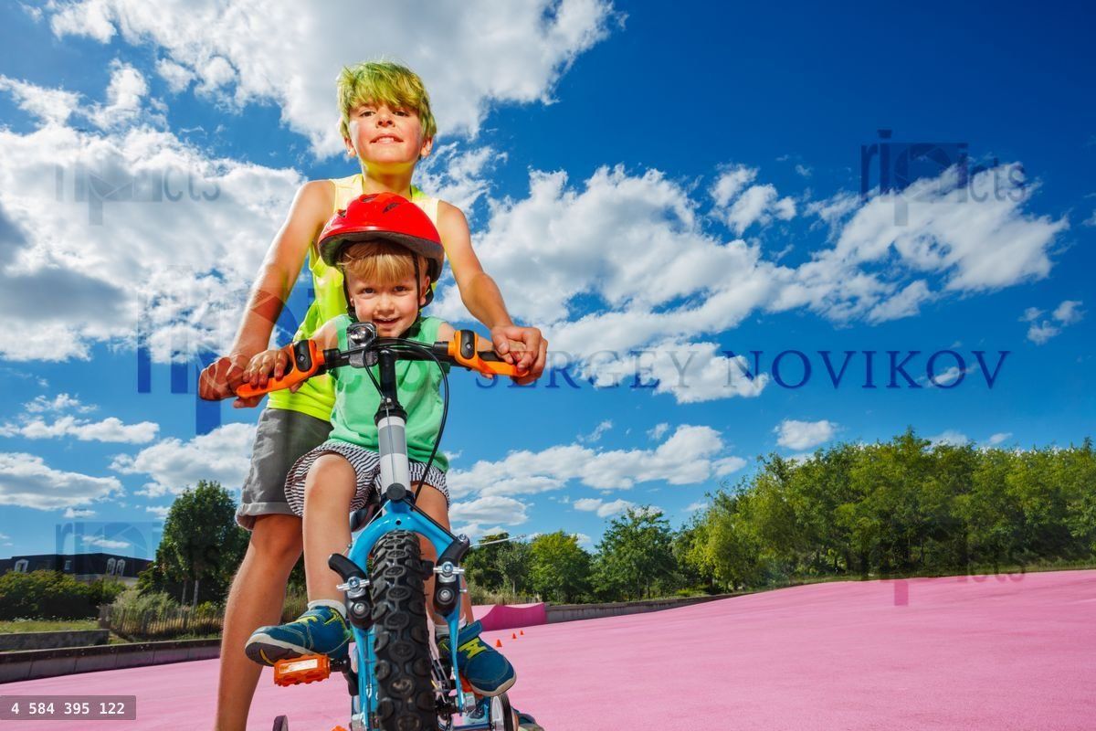 Two children in the park boy teach brother to ride bicycle