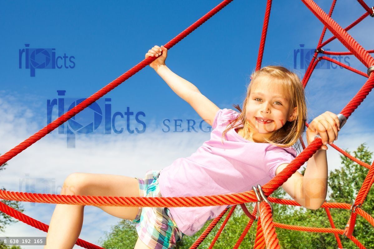 Girl hangs on red net ropes with two arms
