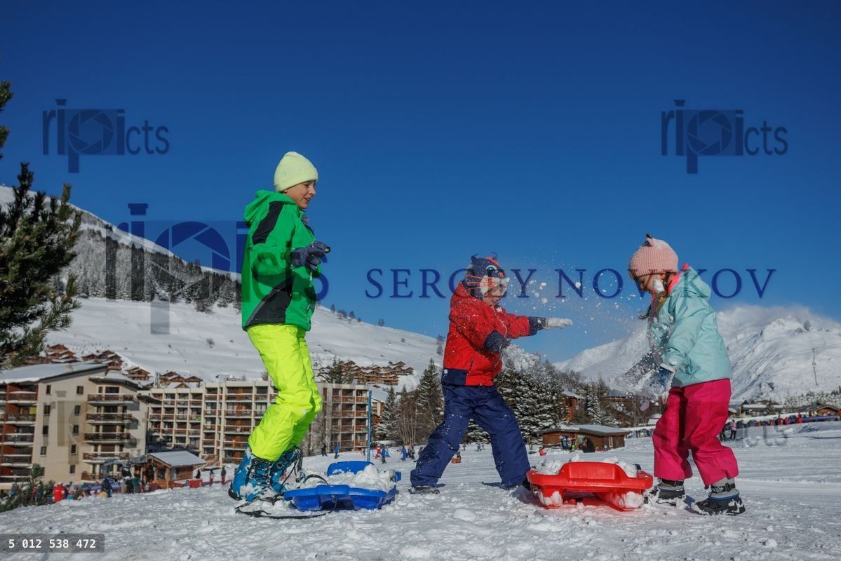 Kids, teen and little siblings play snow fight on snowy slope