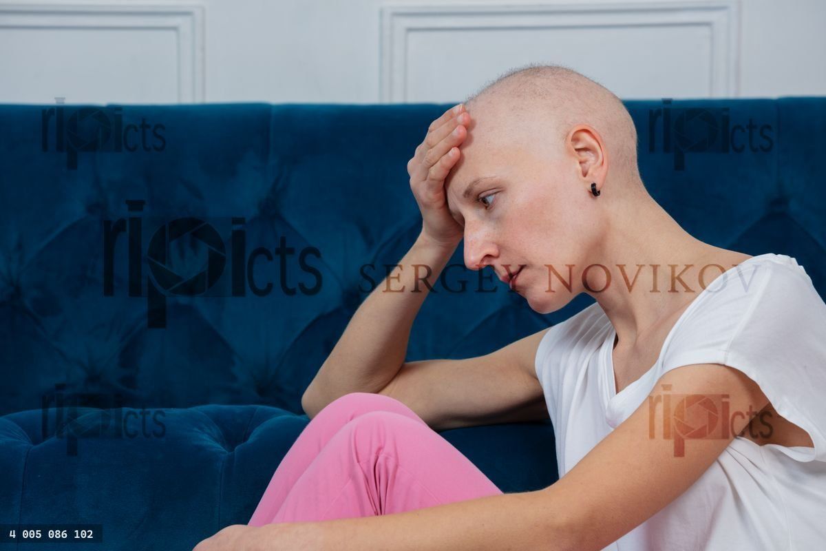 Woman with shaved head sit sadly struggle of chemo side effects