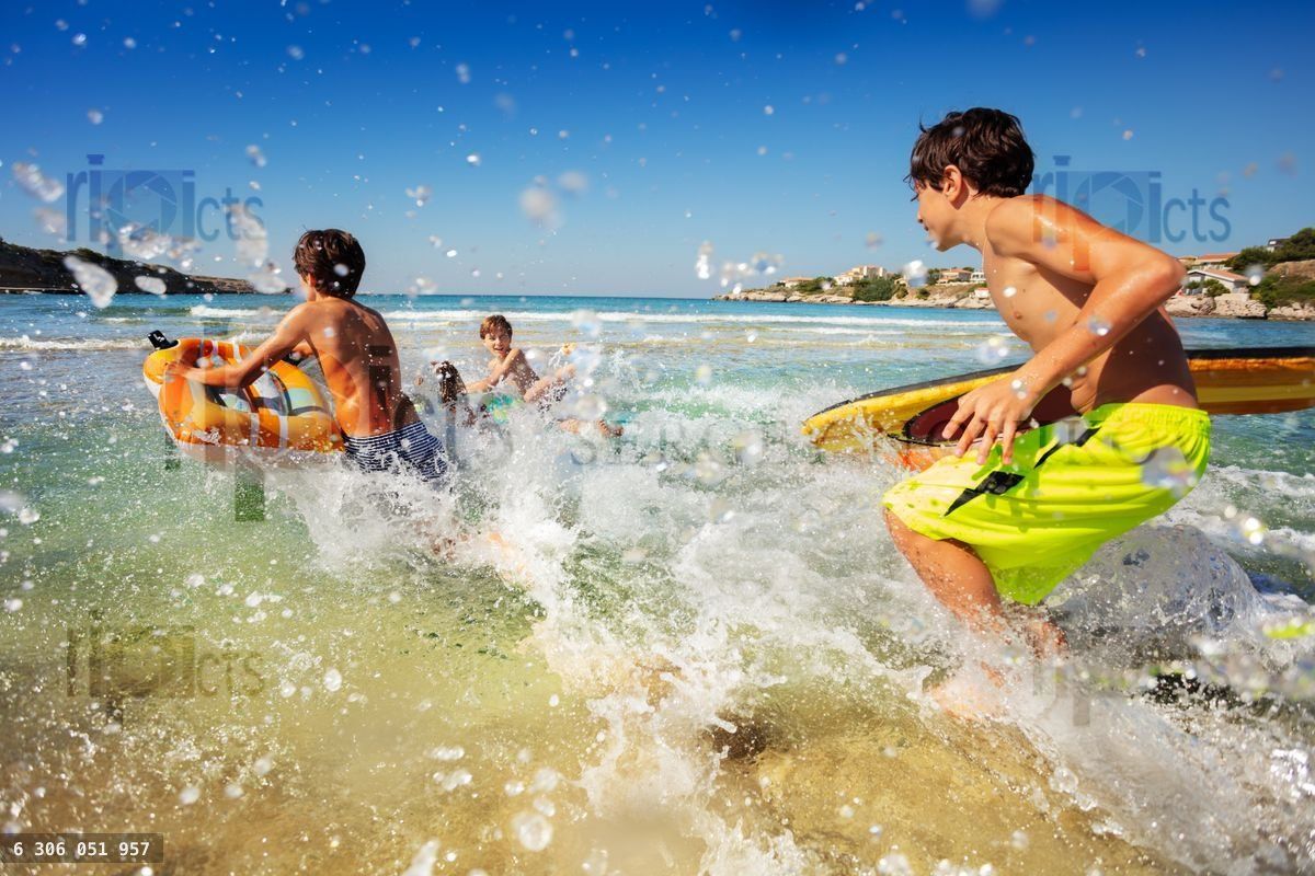 Friends running into the sea with body boards