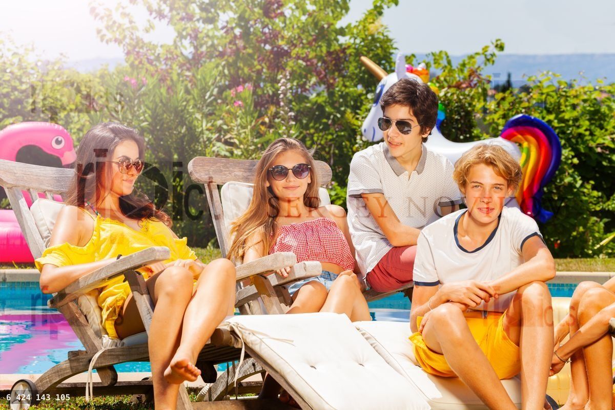 Young smiling teen kids group rest on deck chair
