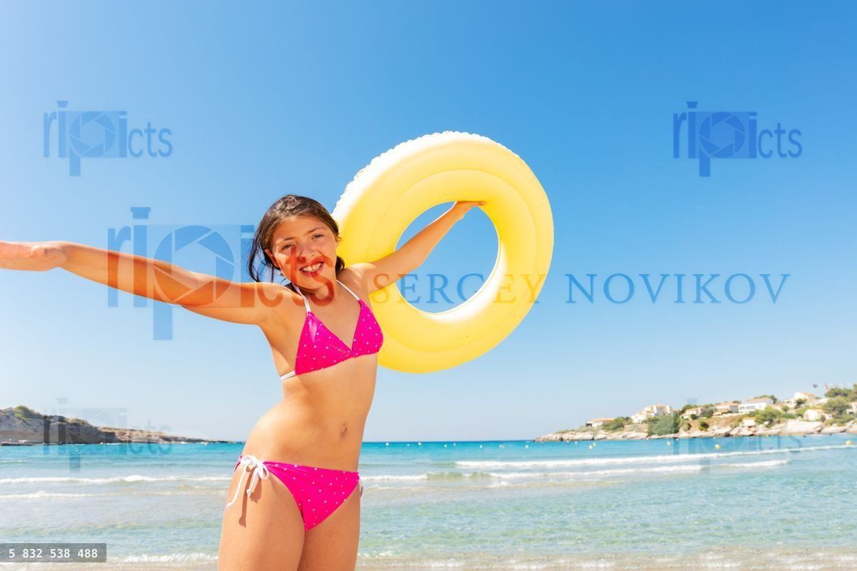Funny girl with yellow rubber ring on the beach
