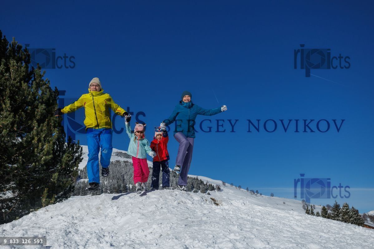 Family of four fun in snow, is capturing joyful winter moments