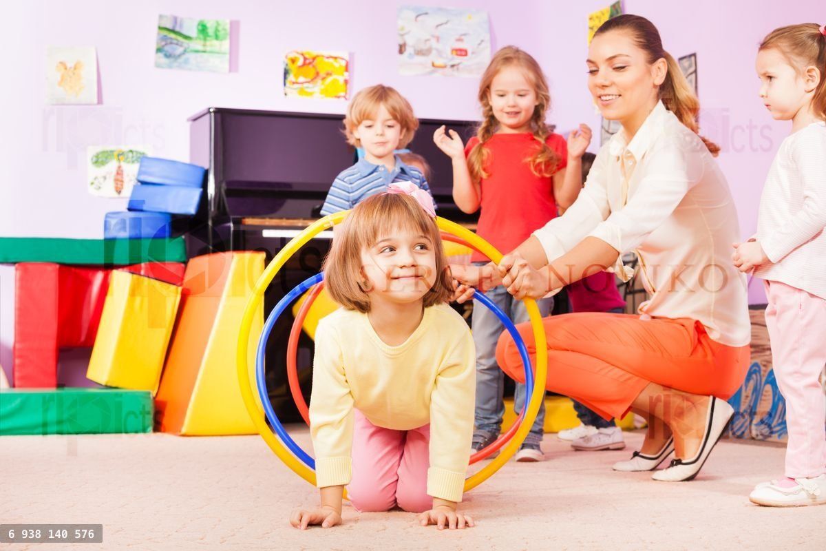 Girl crawl in plastic hoop, kindergarten group