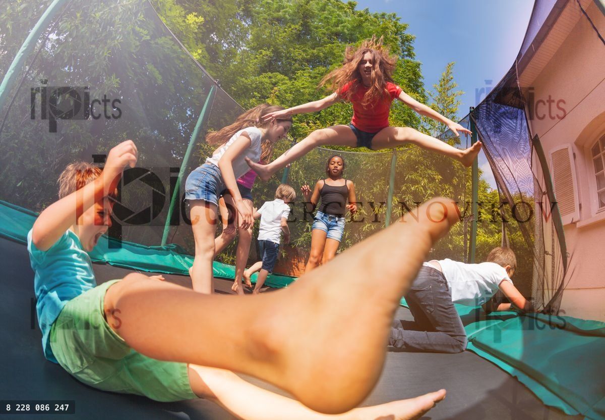 Friends jumping on outdoor trampoline in summer
