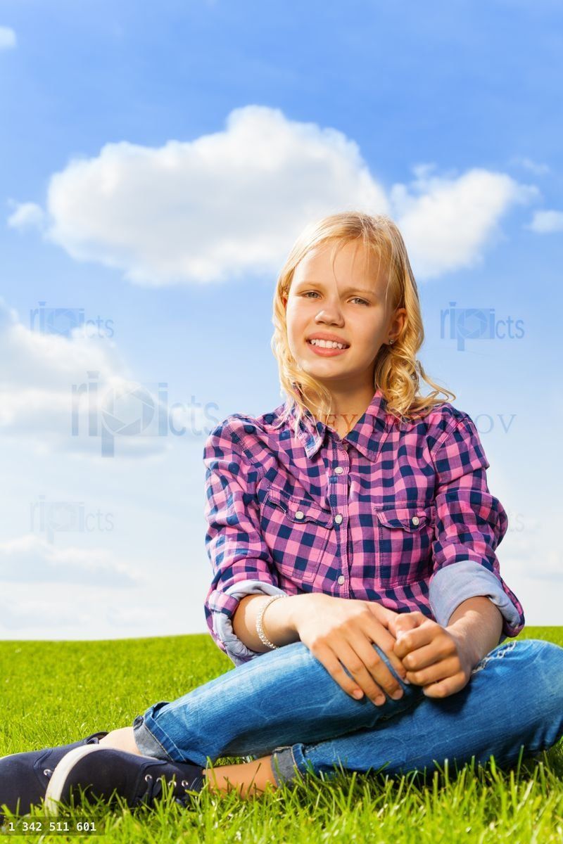 Blond curly girl close up view sitting on grass