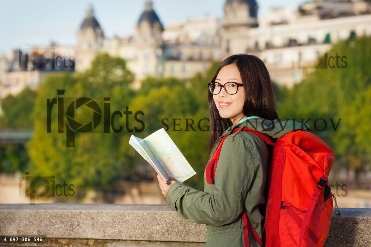 Young girl walking along Seine with map of Paris