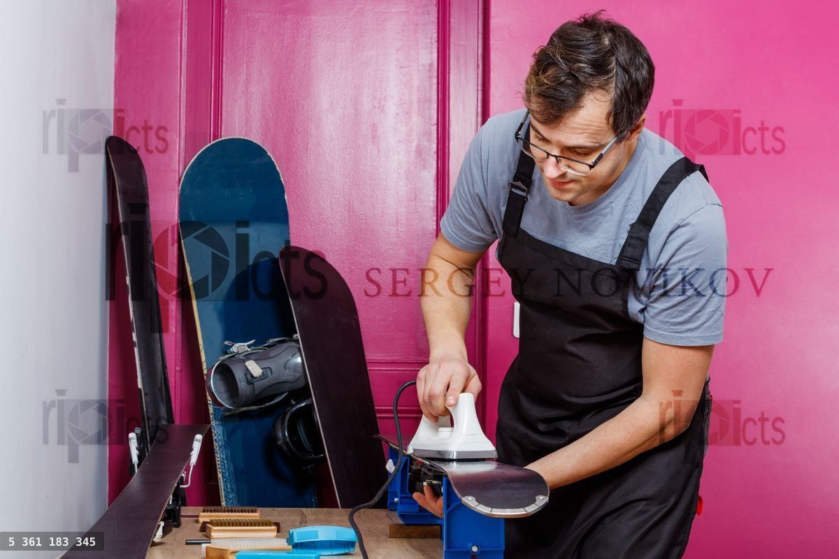 Workshop staff melts wax and apply to enhance ski base glide