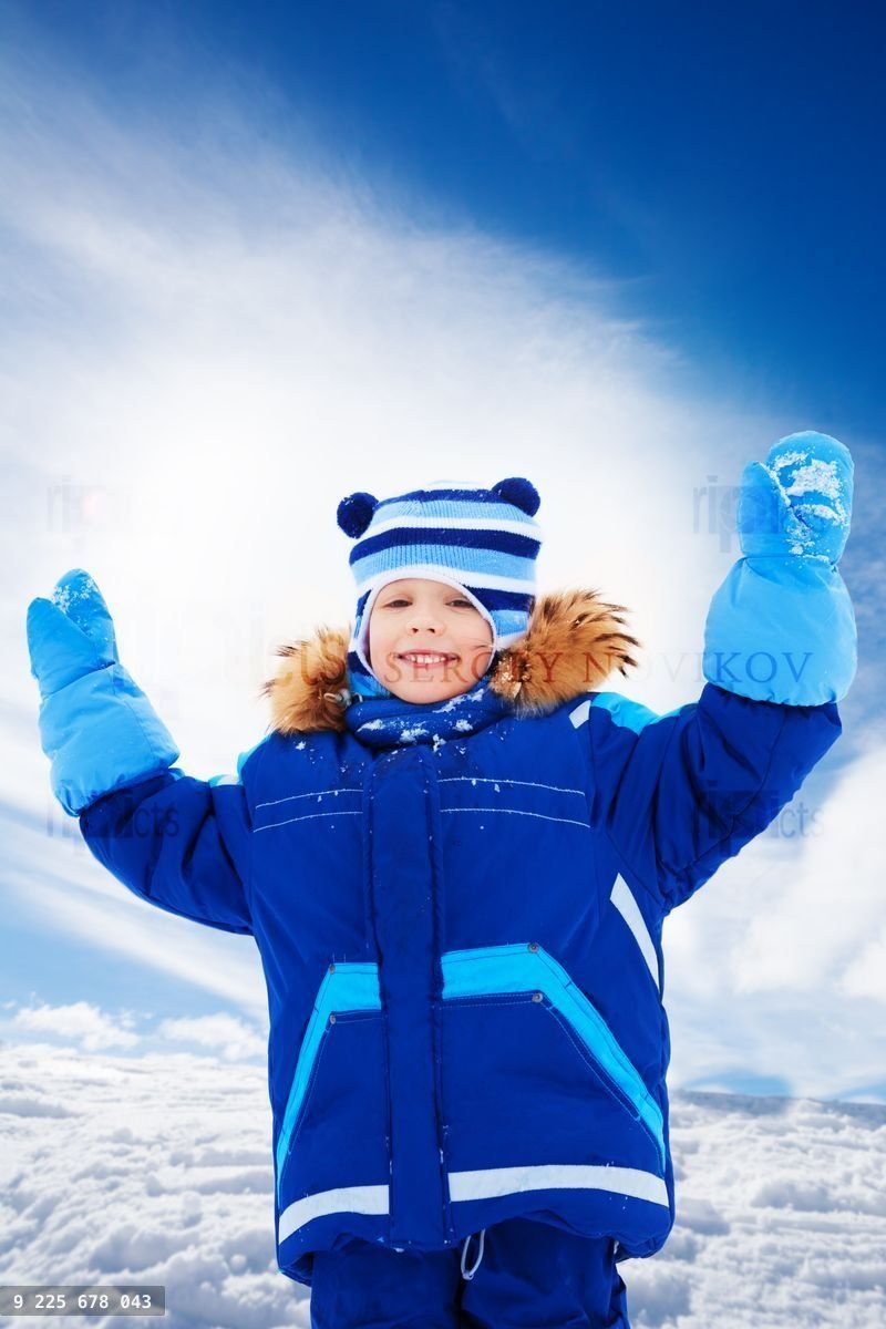 Happy boy standing with sled with lifted hands