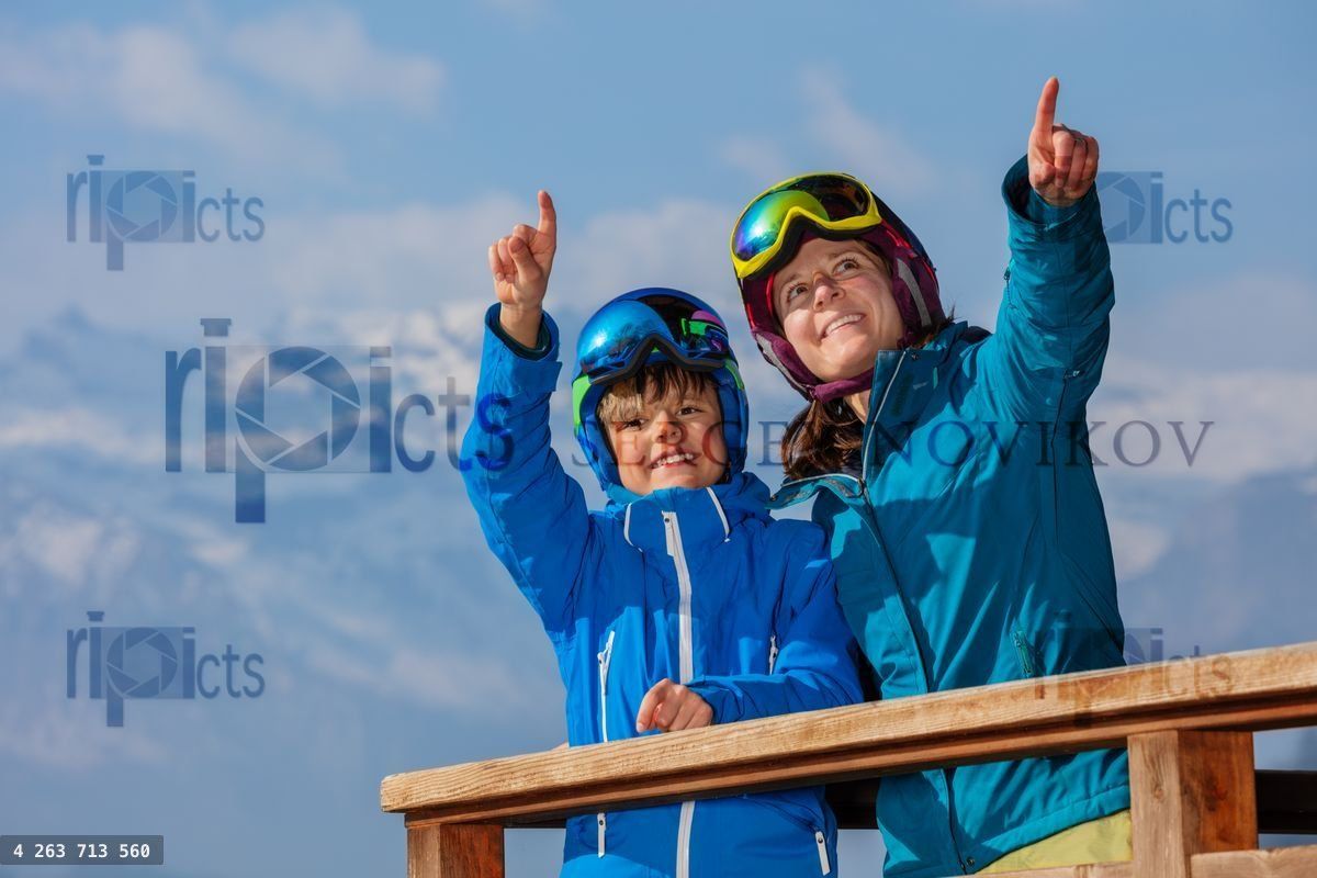 Mother and kid skiers sharing experience showing with finger