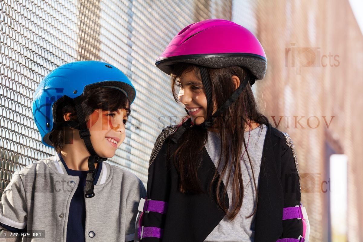Girl and boy in roller helmets having fun outdoors