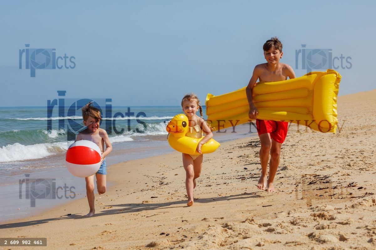 Group of kids playfully race while carry inflatable beach toys