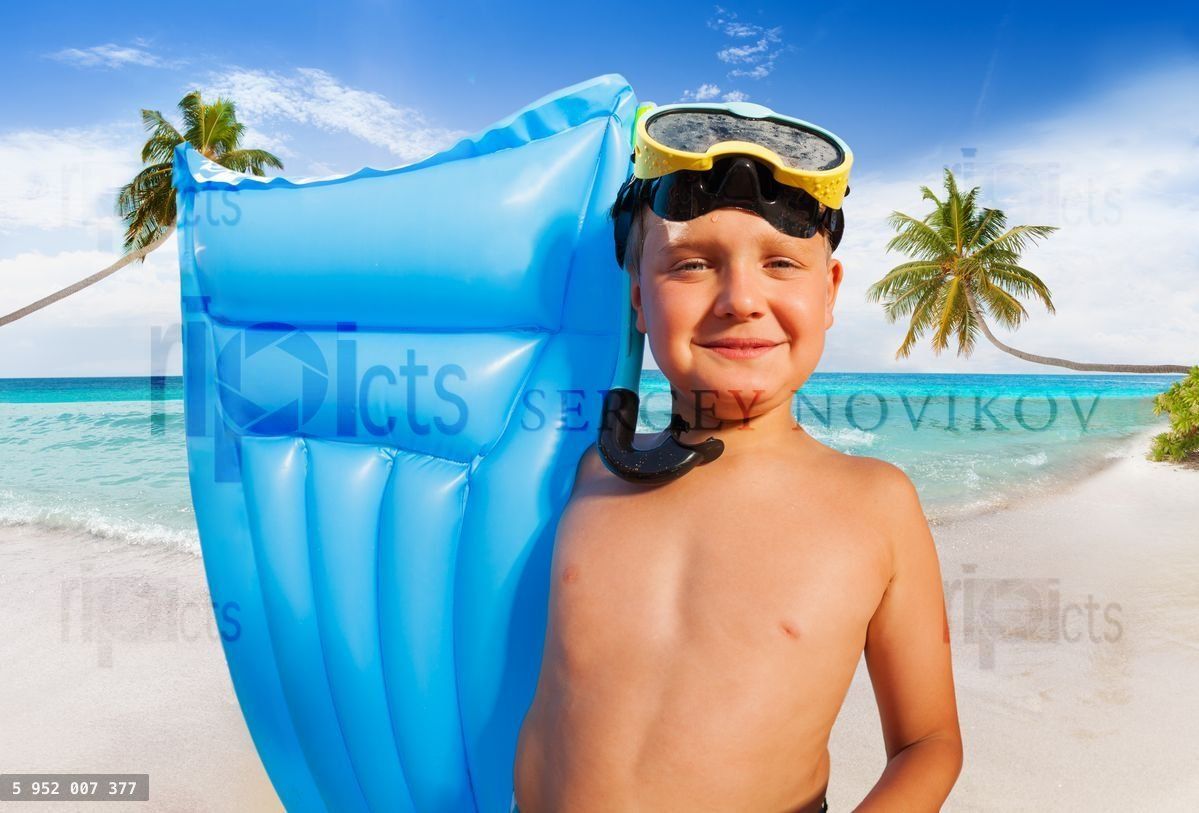 Happy boy with mattress on a palm beach