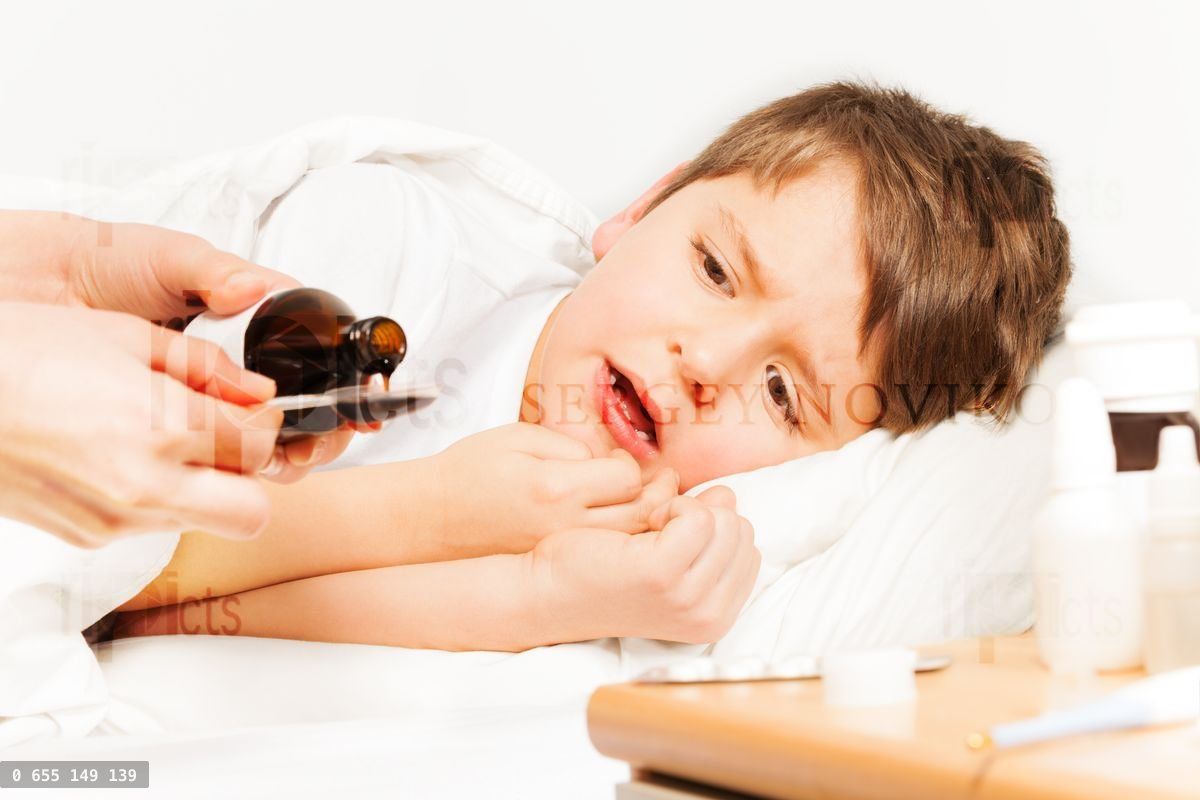 Boy crying while mother pouring coughing syrup