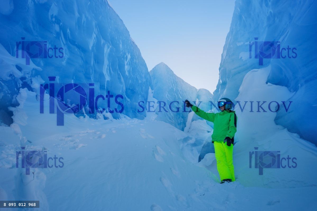 Brightly dressed skier poses in a beautiful ice-filled crevice