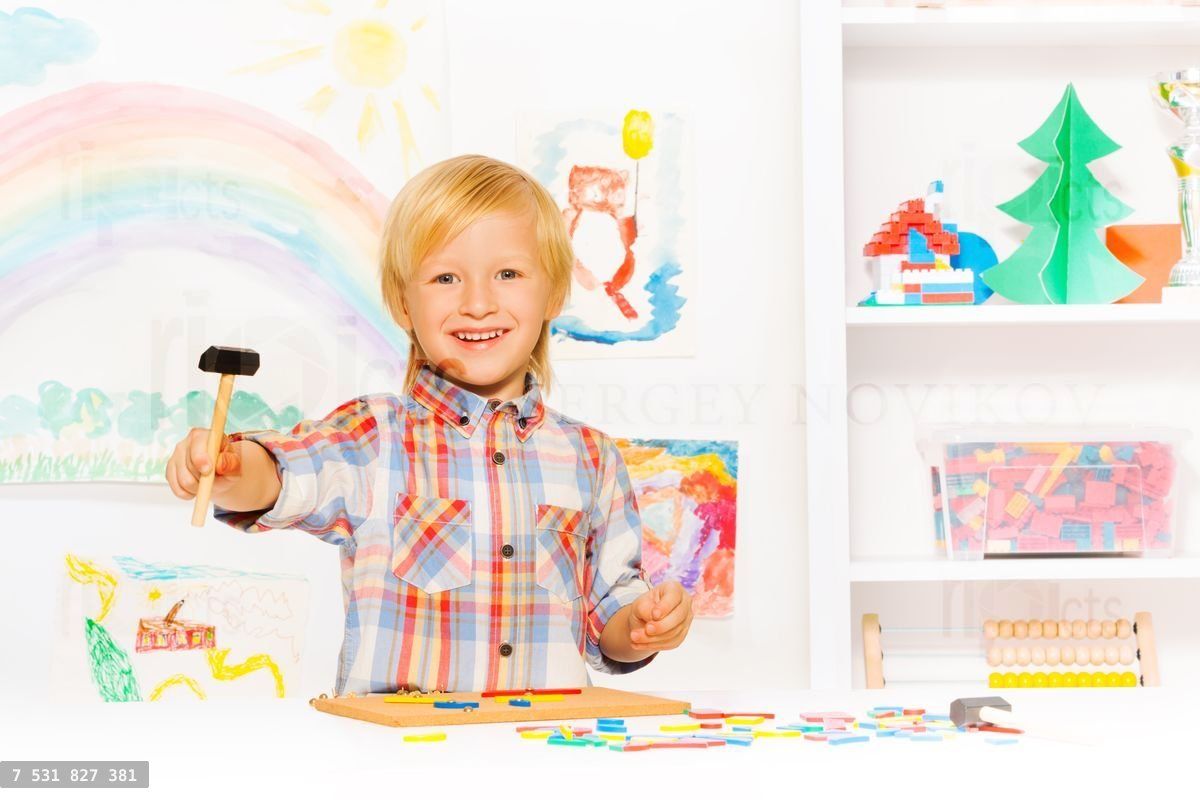 Happy blond boy with hammer and blocks in class