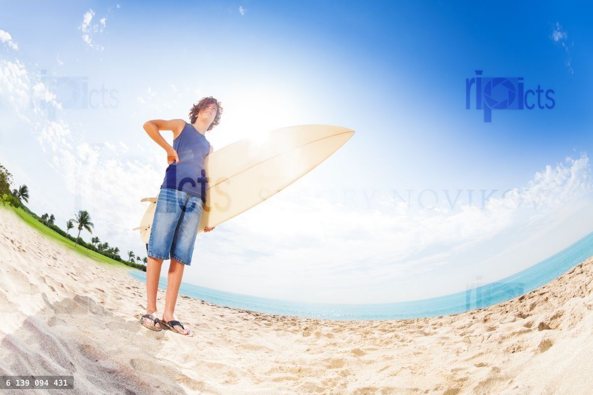 Confident teenager on beach with surfboard