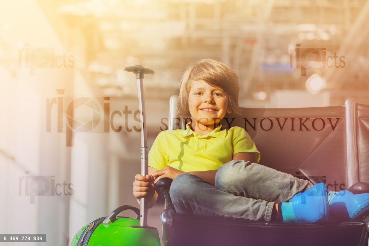 Happy boy with suitcase at the departure lounge